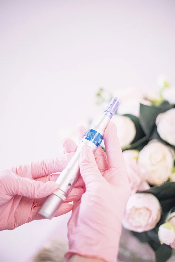 Microneedling pen held in pink gloves