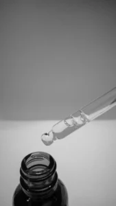 Glass dropper above a dark bottle