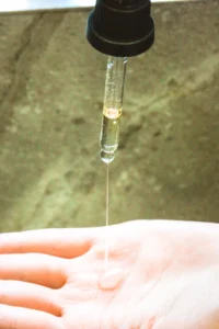 Serum drop falling onto a hand